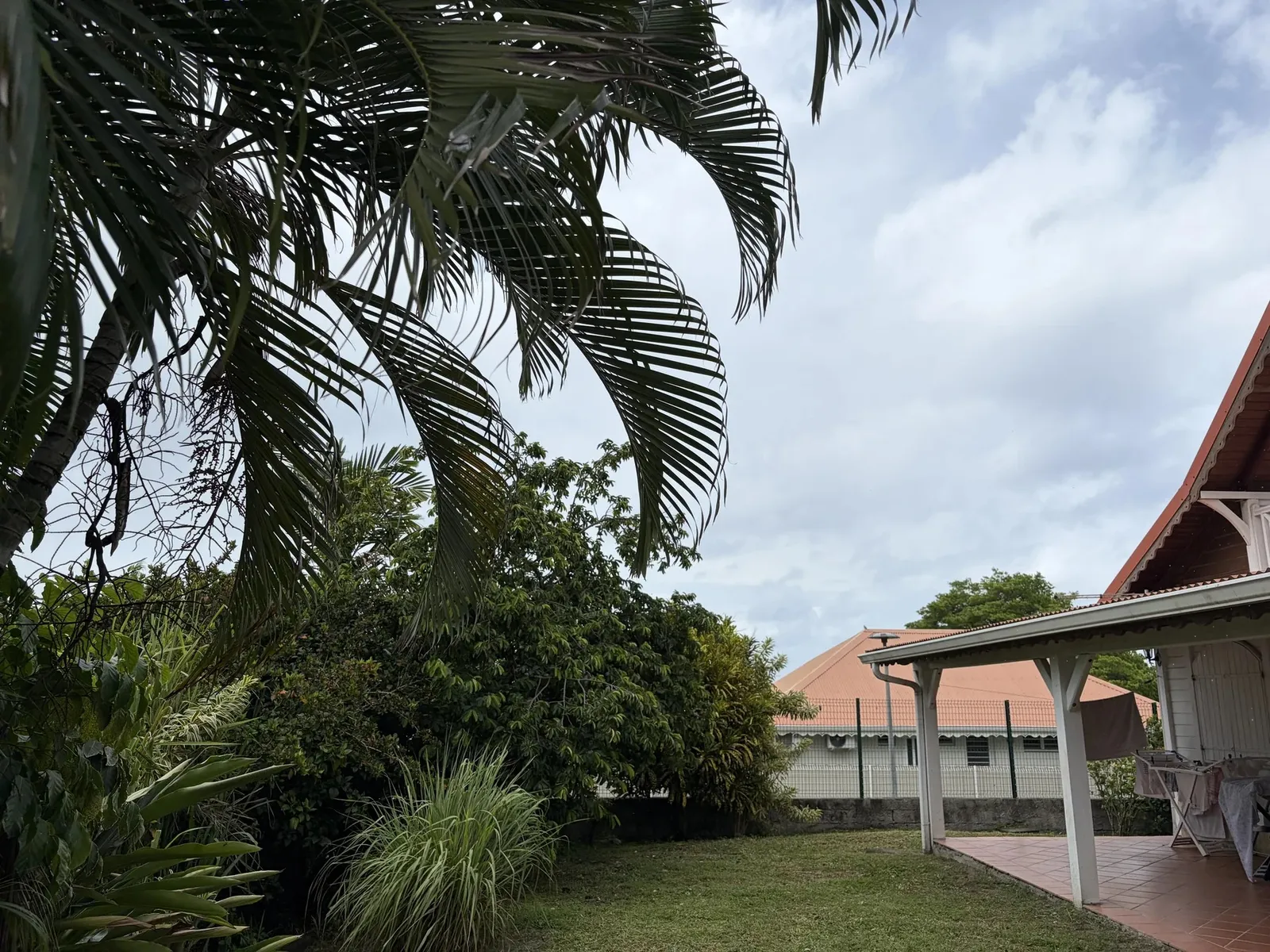 Jardin tropical de la villa avec palmiers et terrasse couverte