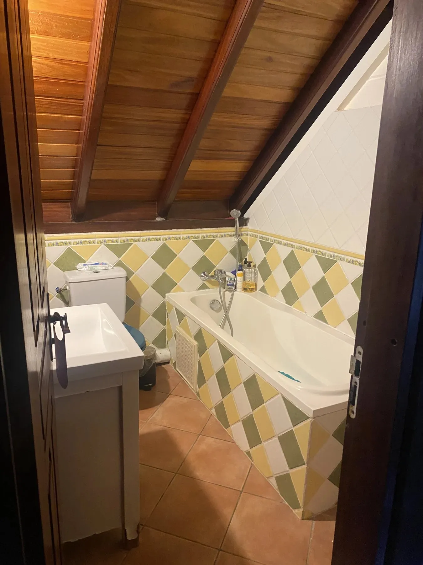 Salle de bain mansardée de la villa avec baignoire et carrelage artisanal jaune et vert