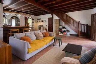 Salon de la villa avec canapés, poutres en bois apparentes et escalier en bois