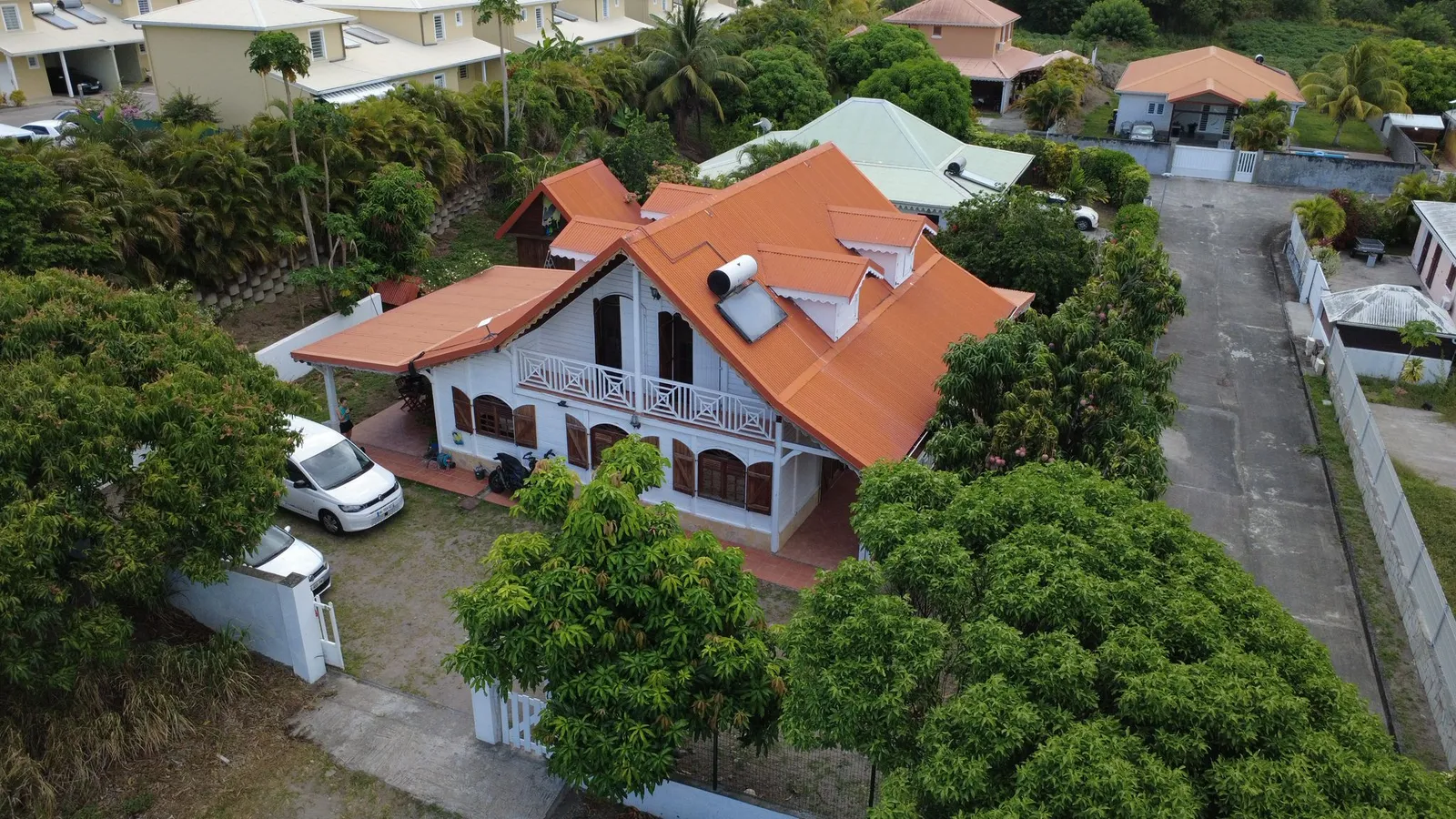 Vue aérienne de la Villa Bas-Pellée entourée de son jardin tropical et de manguiers, mer des Caraïbes au loin