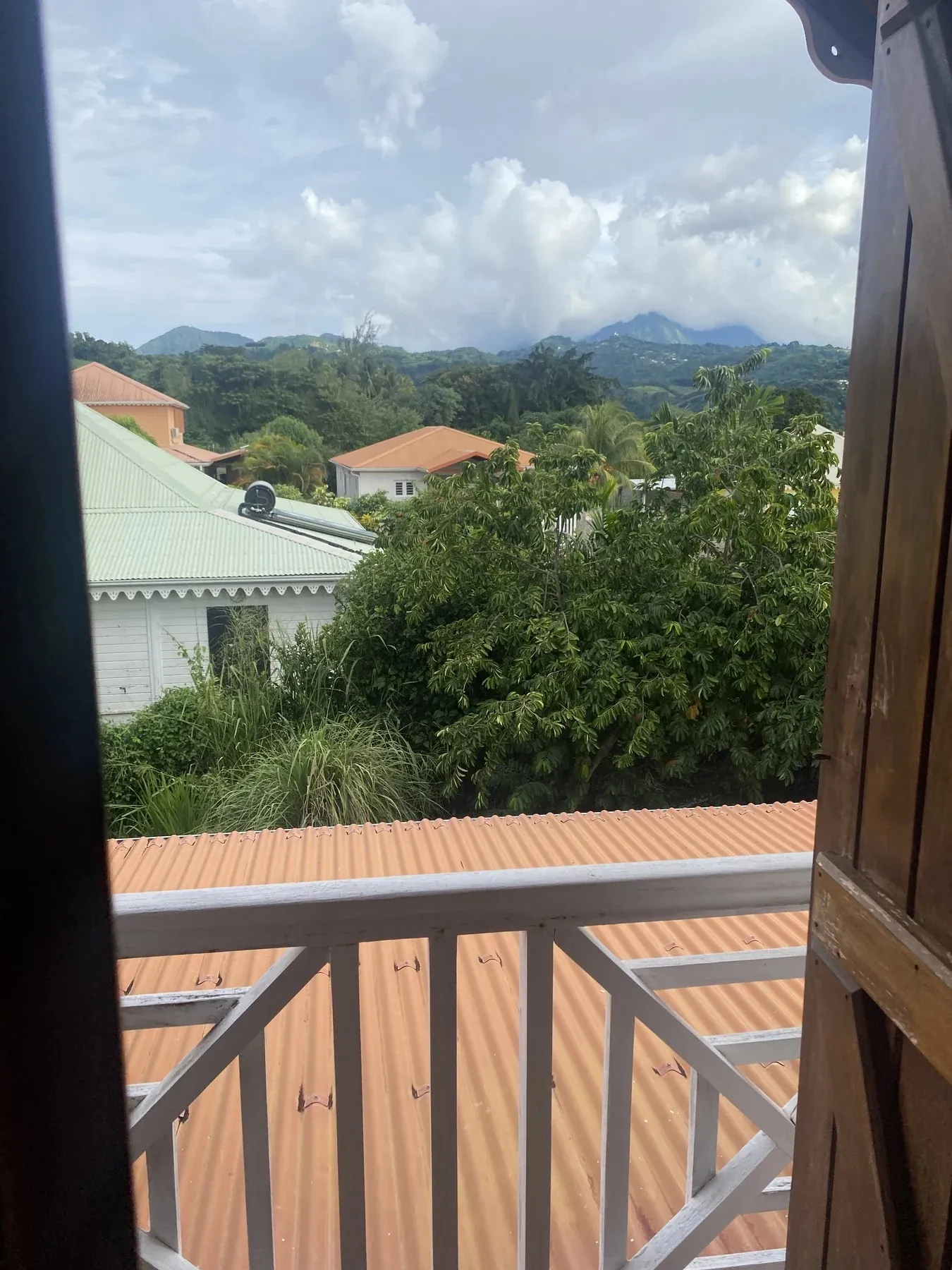 Vue sur les mornes verdoyants depuis le balcon en bois de la villa